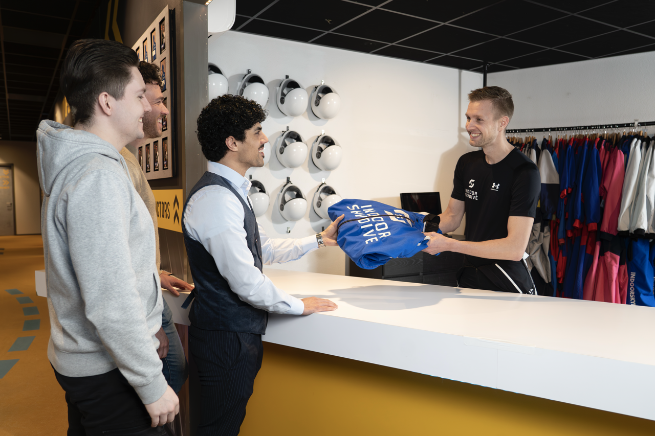 Medewerker overhandigt skydivekleding